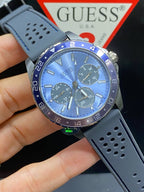 ساعة Guess Odyssey W1108G6 بهيكل بلون رصاصي داكن، ومينا أزرق سماوي، وحزام مطاطي رمادي